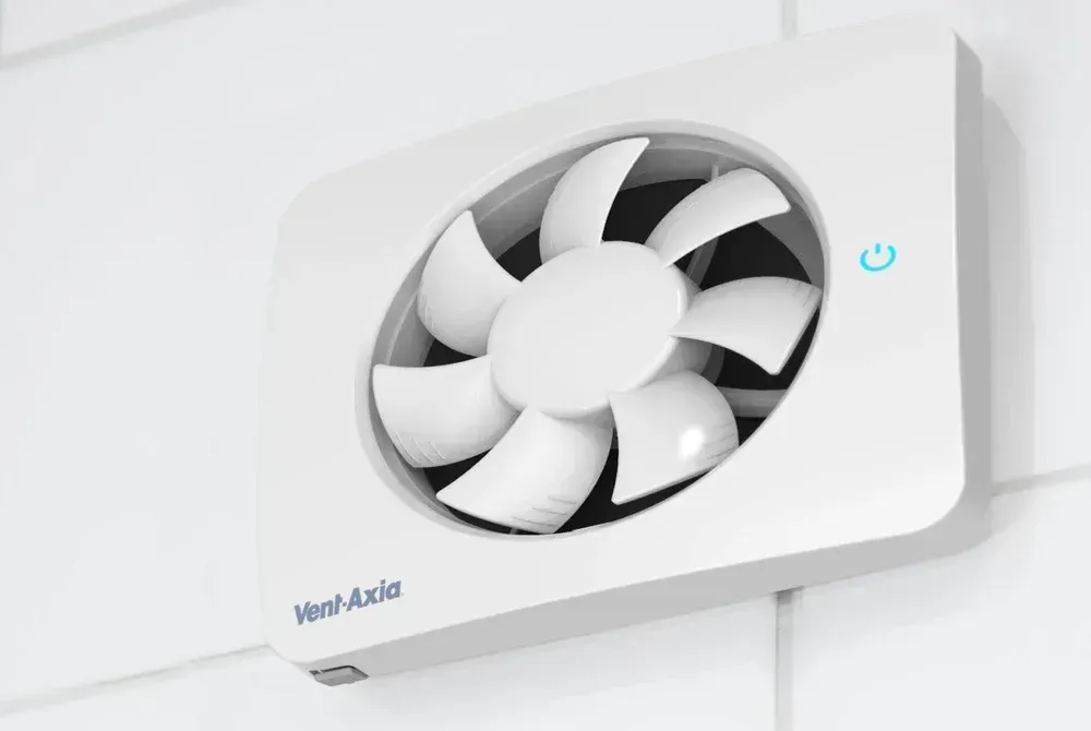 A white fan is mounted to a white wall