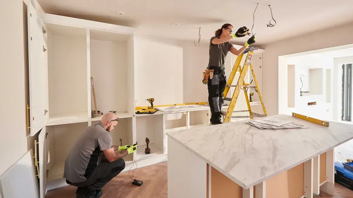 A man and a woman are working on a kitchen.